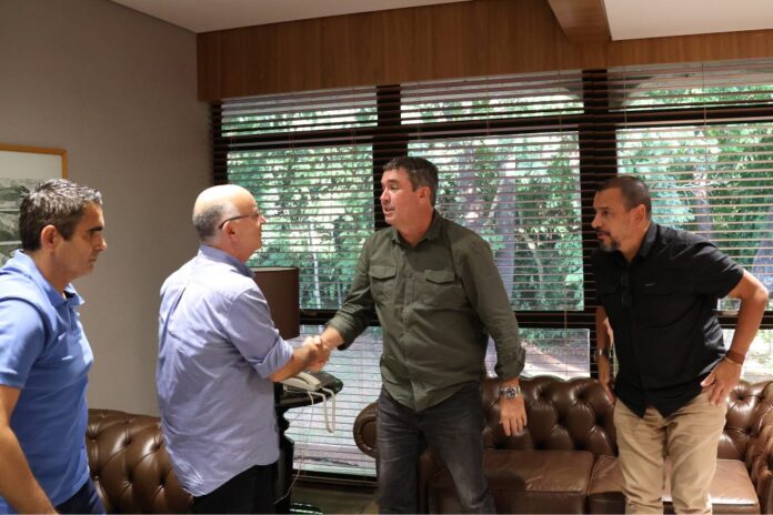 CBV reforça parceria com Governo de MS e destaca Estado Governador de camisa verde cumprimenta Radamés Lattari, que está de camisa azul claro.